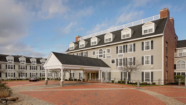A multi-story building with a covered entrance and a brick driveway.