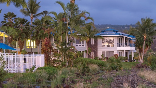 A beachfront property with a waterfall, palm trees, and a house with a blue roof. - Holua Resort (Kailua-Kona)