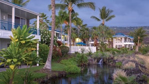 A hotel with a pool, palm trees, and a waterfall. - Holua Resort (Kailua-Kona)