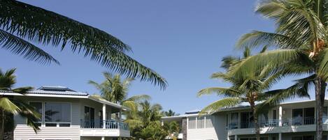 A resort with two-story buildings, a pool, and palm trees.