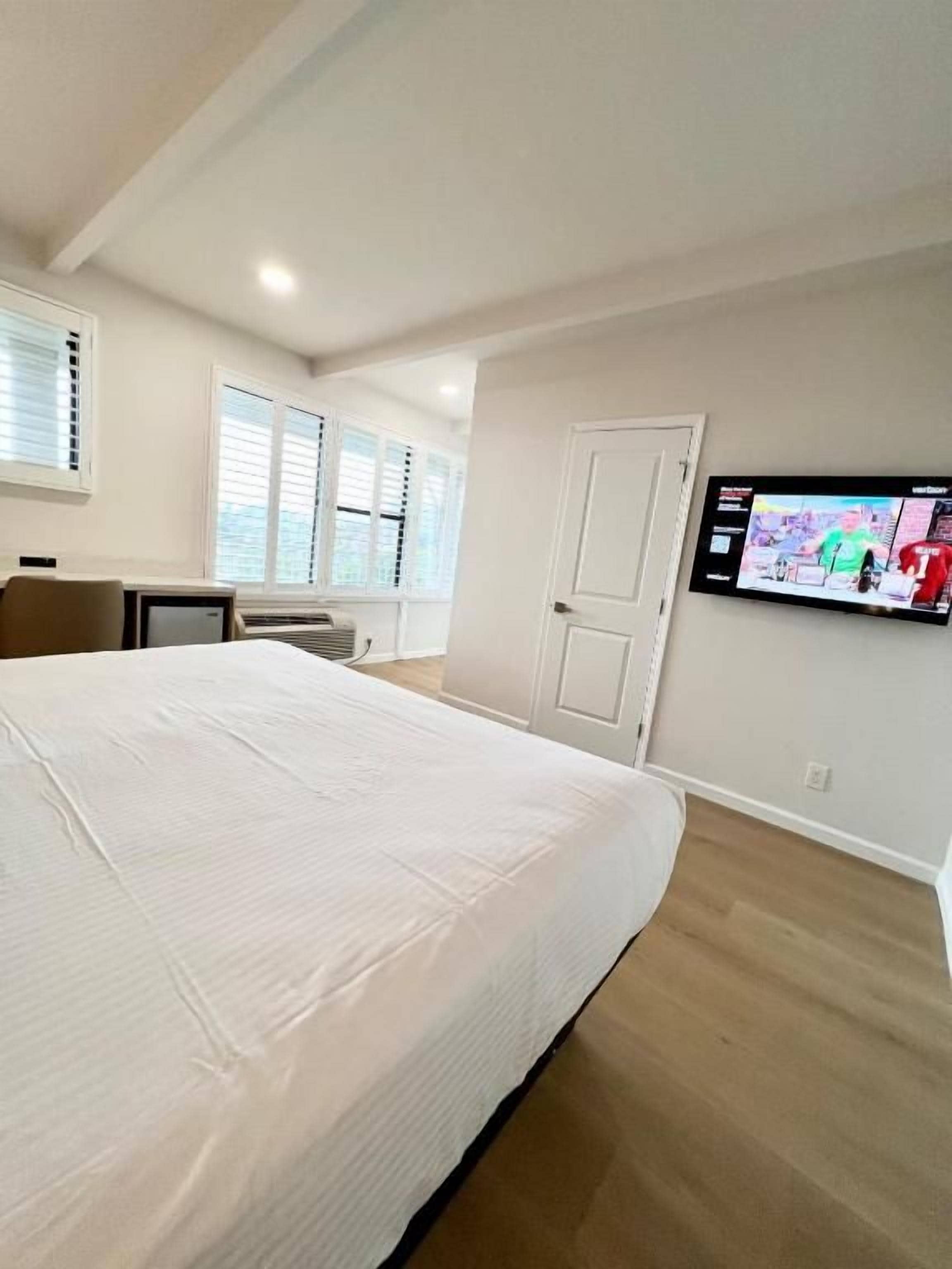 A bedroom with a bed, a television on the wall, and a door.