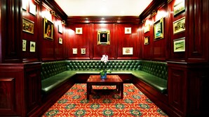A room with a green leather sofa, a wooden table, and a patterned carpet.