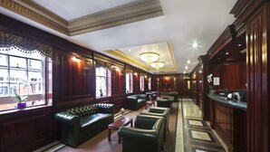 A spacious lobby with leather seating, a reception desk, and a chandelier.