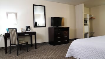 A hotel room with a bed, a desk, a chair, a television, a dresser, and a wardrobe.
