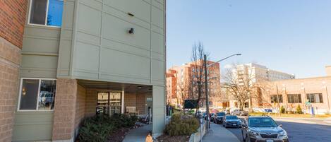 A modern building with a brick facade, a fire hydrant, and parked cars along the street.