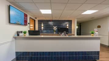 Zona de recepción con pared de azulejos, mostrador y monitor.