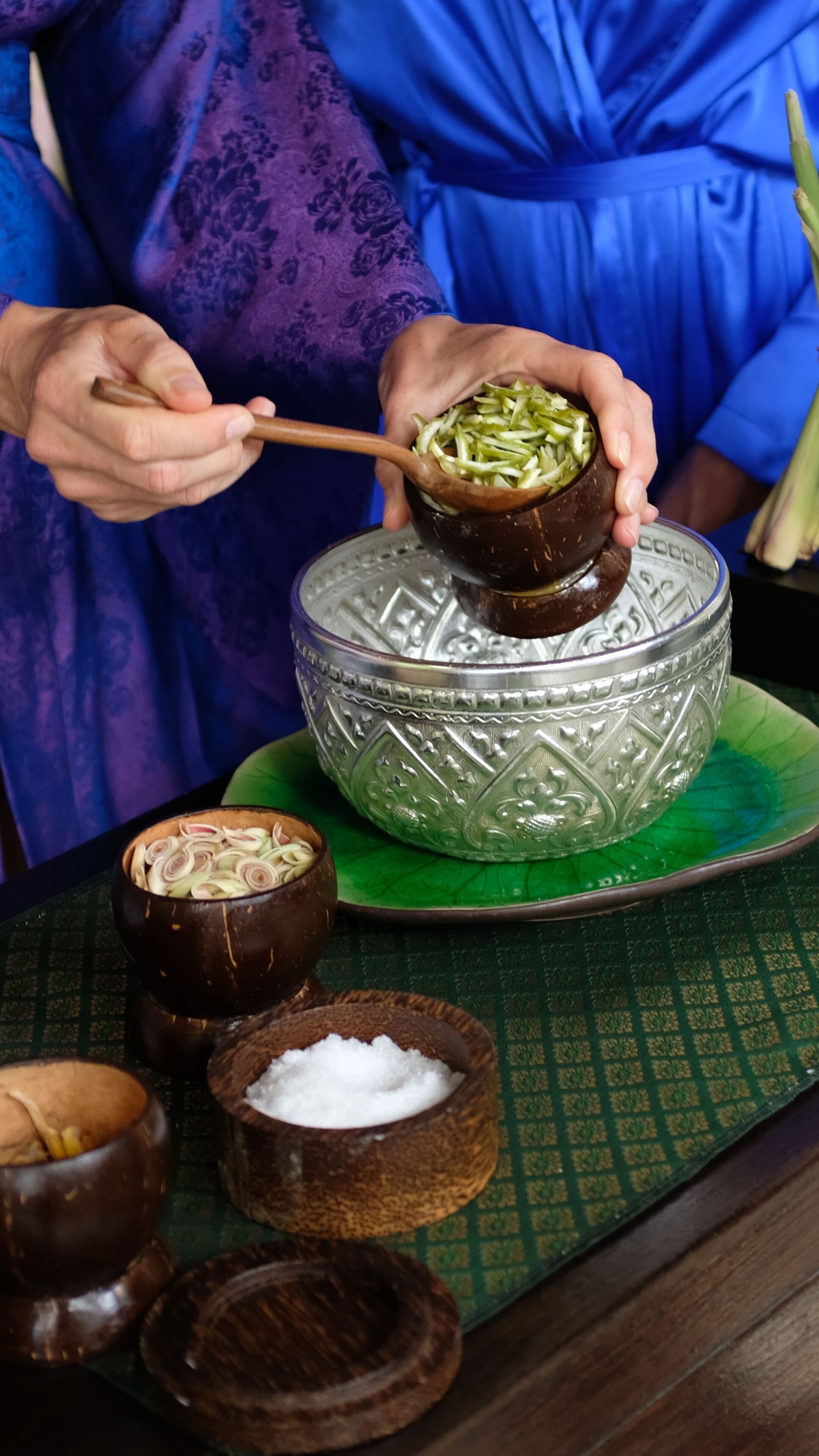 Una persona preparando un plato con palillos, un cuenco decorativo y recipientes pequeños con ingredientes.
