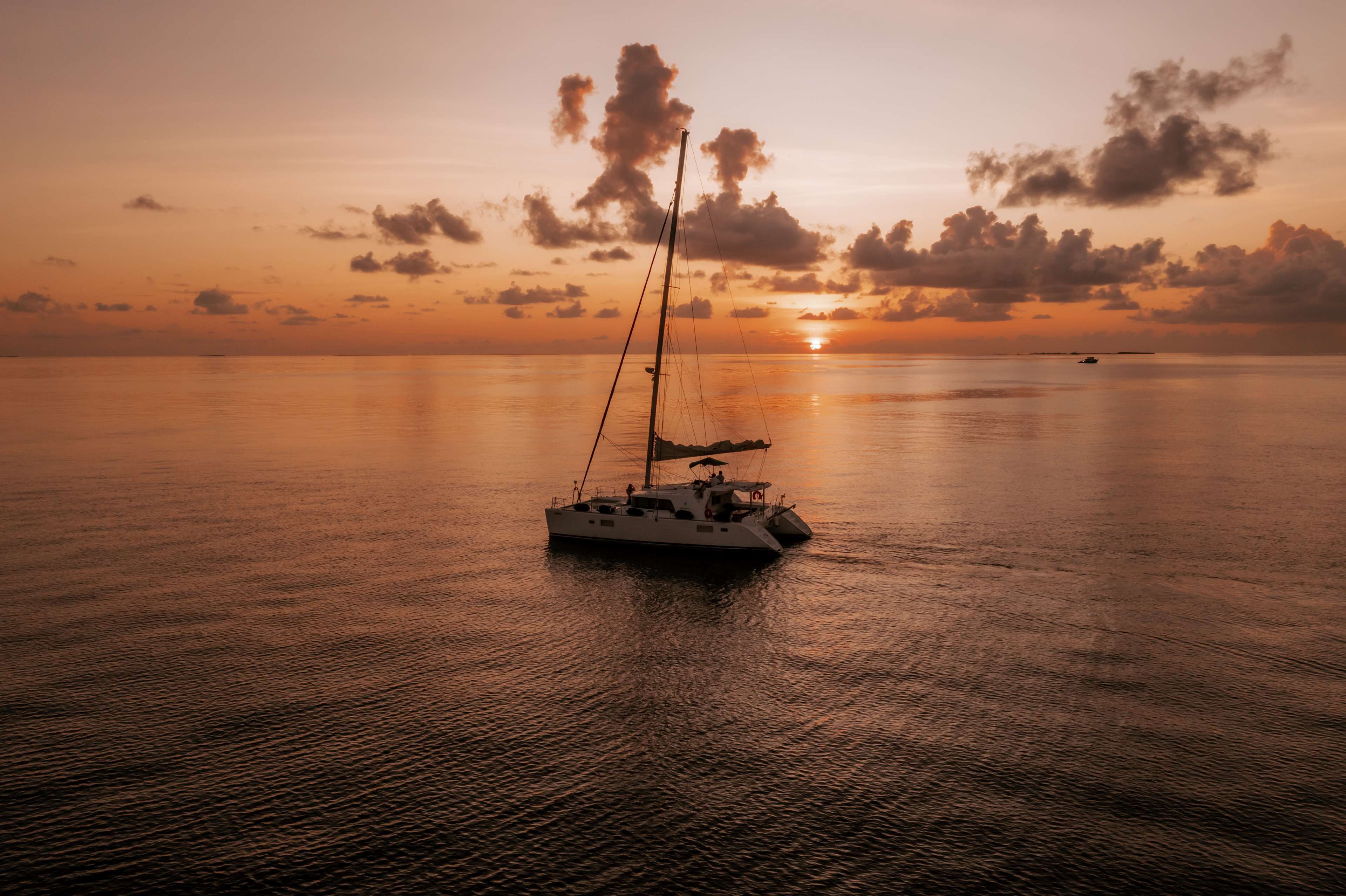 A sailboat on calm waters during sunset.