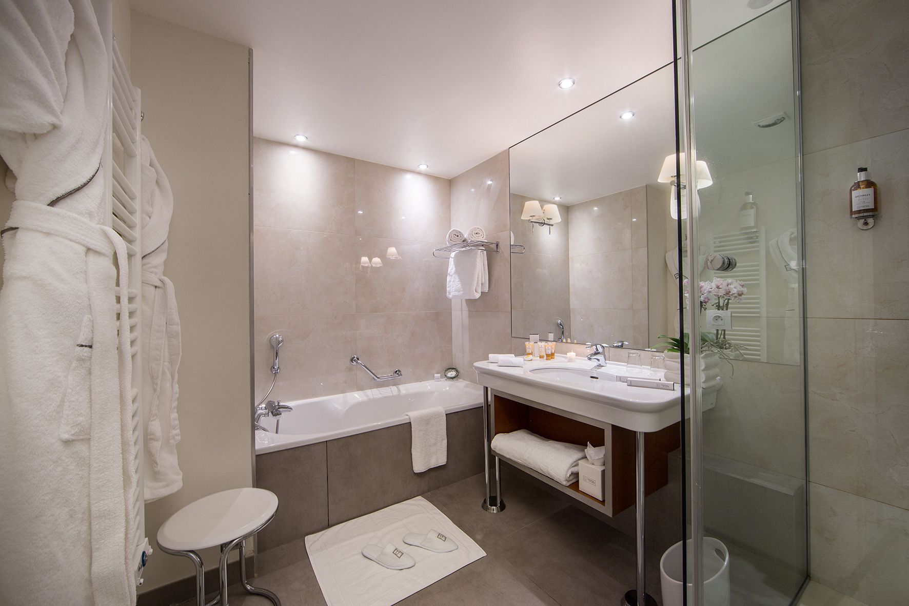 Ein modernes Badezimmer mit Badewanne, Waschtisch mit Spiegel und einer Duschkabine aus Glas.