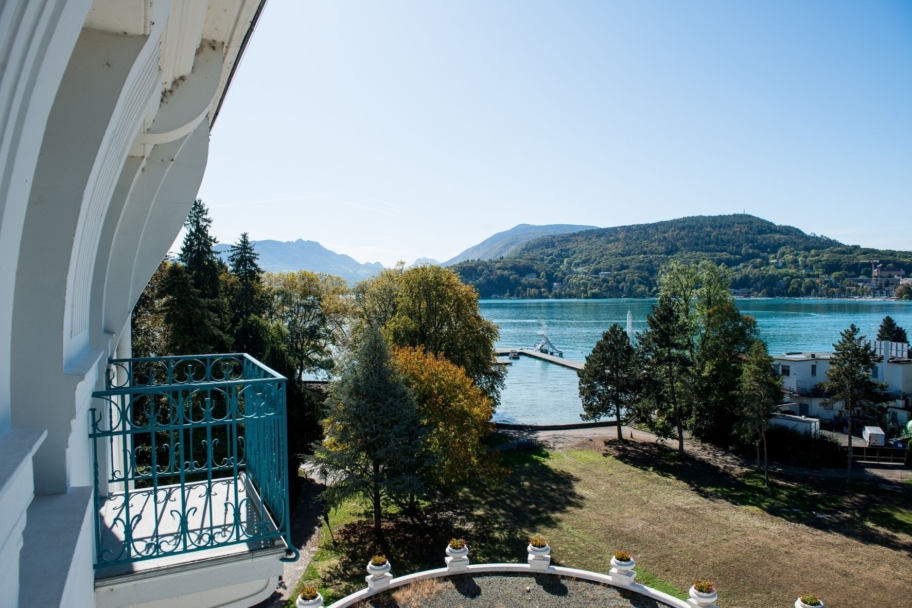 A balcony with a view of a lake, trees, and distant mountains.
