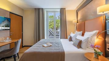 Habitación de hotel con cama, mesita de noche, lámpara y vistas al exterior.