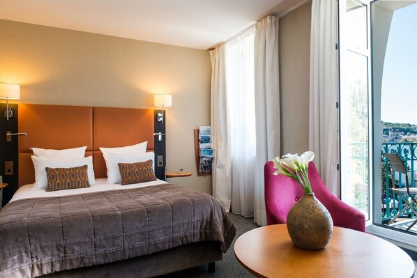 A hotel room with a bed, a nightstand, a vase with flowers, and a view of the outside balcony.