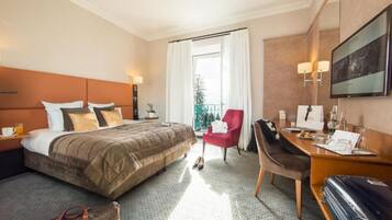 A hotel room with a bed, a desk, a chair, a suitcase, and a balcony with a view.