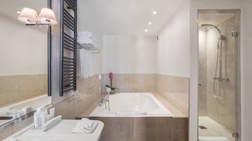 A modern bathroom with a large bathtub, a glass-enclosed shower, and a vanity with a mirror and towel rack.