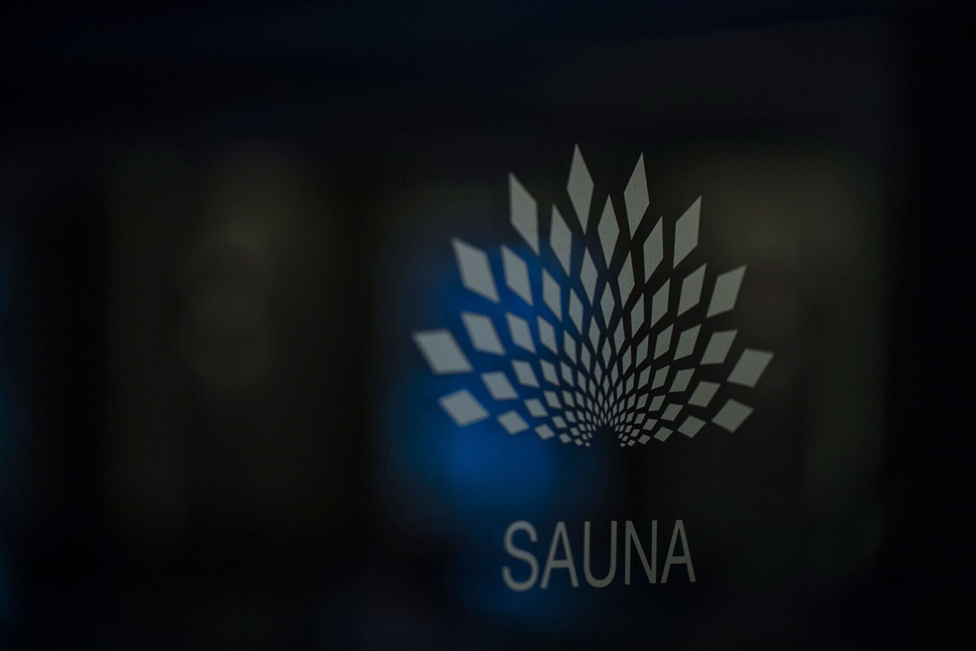 Een logo met het woord 'SAUNA' op een donkere achtergrond.