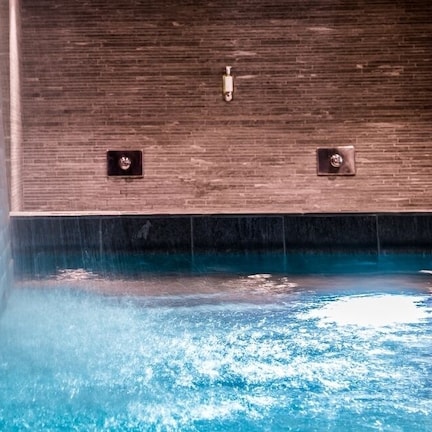 A modern indoor pool with a brick wall and a wooden panel wall.