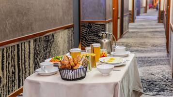 A breakfast setup with eggs, bread, and beverages on a table in a hotel corridor.