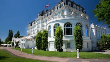 A large, white, classical-style building with multiple balconies and arched windows.