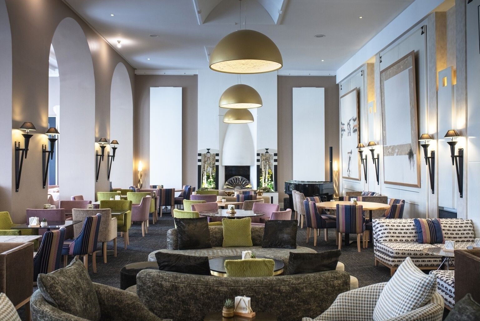 A spacious lounge area with multiple seating arrangements, including sofas and chairs, and a piano in the center.
