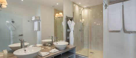 Une salle de bain moderne avec deux grands lavabos, une douche à l’italienne et un grand miroir.