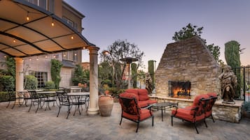 Relax in a cozy seating area surrounded by lush greenery and a stone-built fireplace.