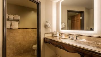 A bathroom with a marble sink, a large mirror, and a towel rack with towels.