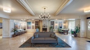 A spacious living room with a fireplace, a chandelier, and a large sofa. There are multiple seating areas and a dining table. - Ayres Hotel Seal Beach - Cypress (Seal Beach)