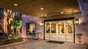 A building entrance with a stone facade, arched doorways, and potted plants. - Ayres Hotel Seal Beach - Cypress (Seal Beach)