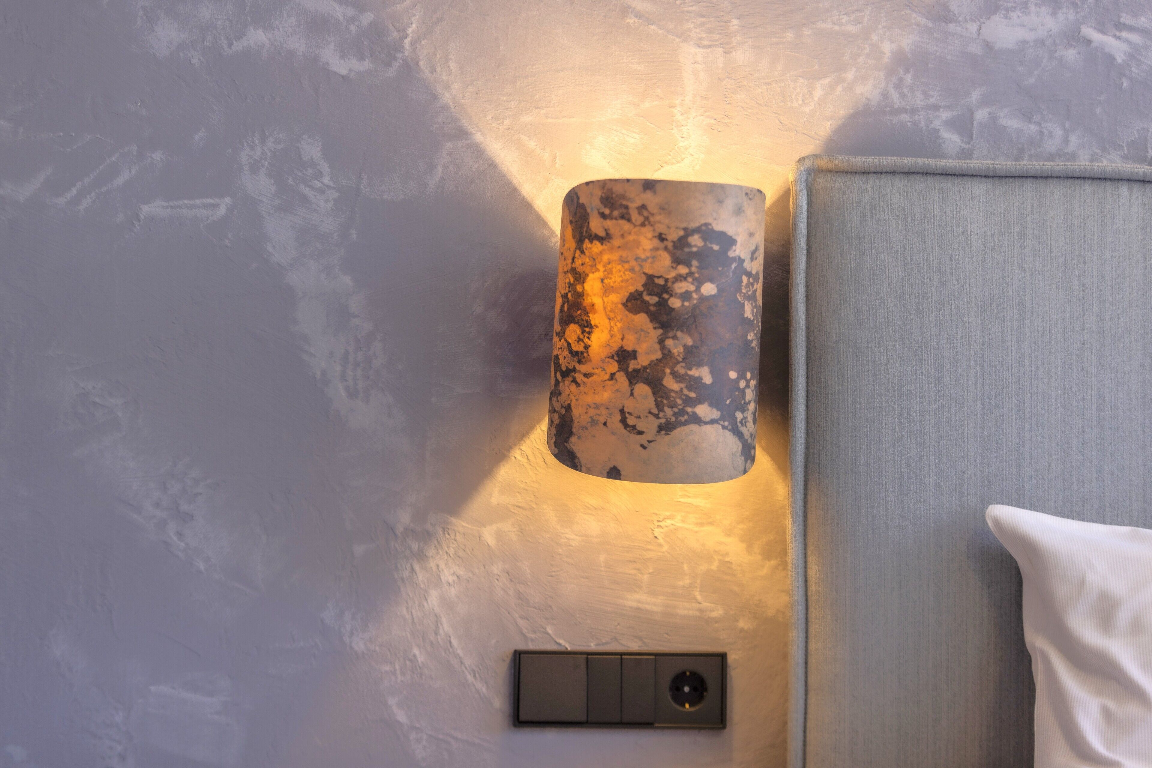 A wall-mounted light fixture with a textured, metallic finish.