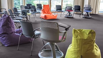 A conference room with multiple chairs and bean bags, large windows with a view of greenery outside.
