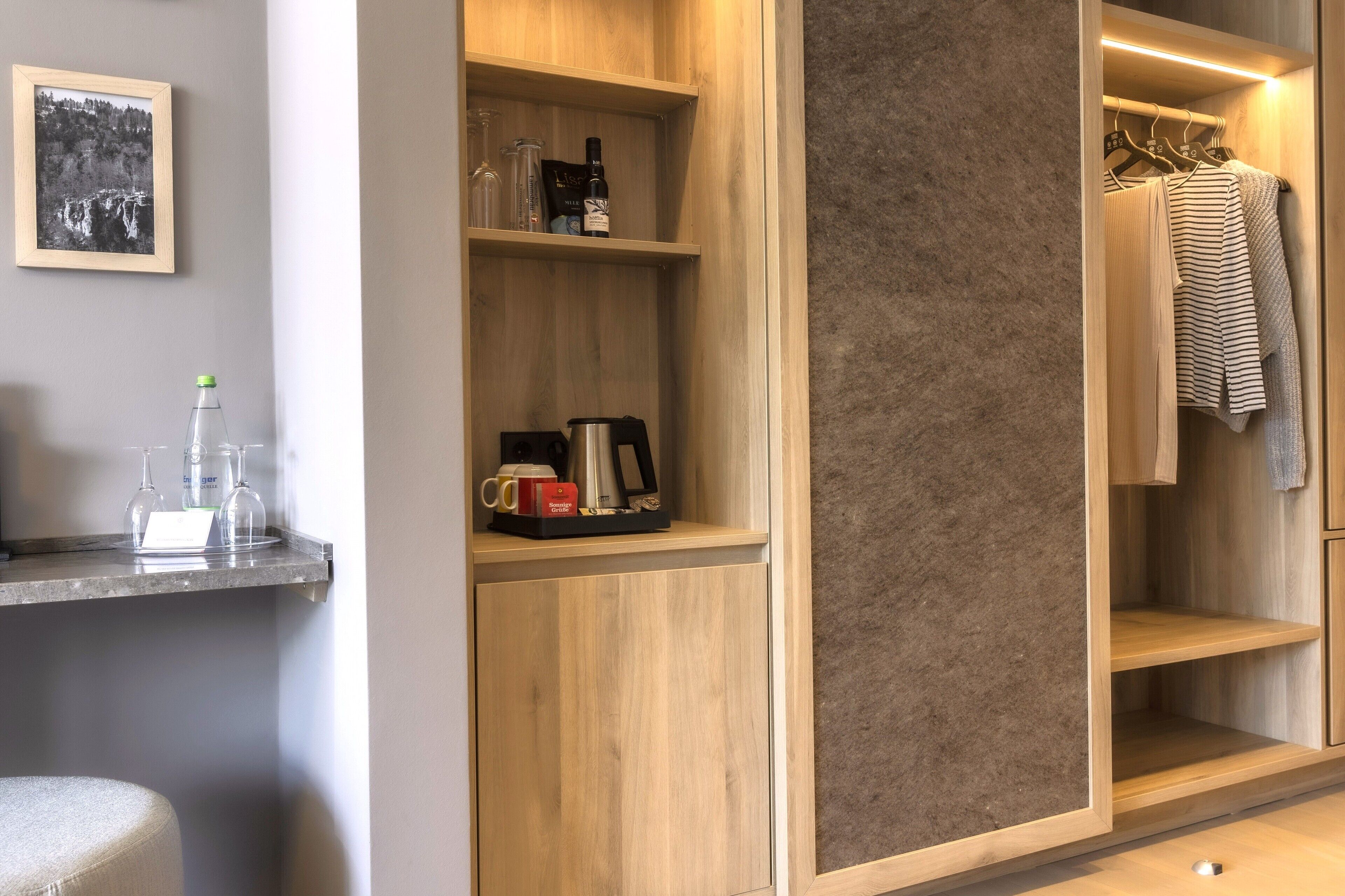 A modern bathroom with a wooden vanity, a towel rack, and a shelf with toiletries.