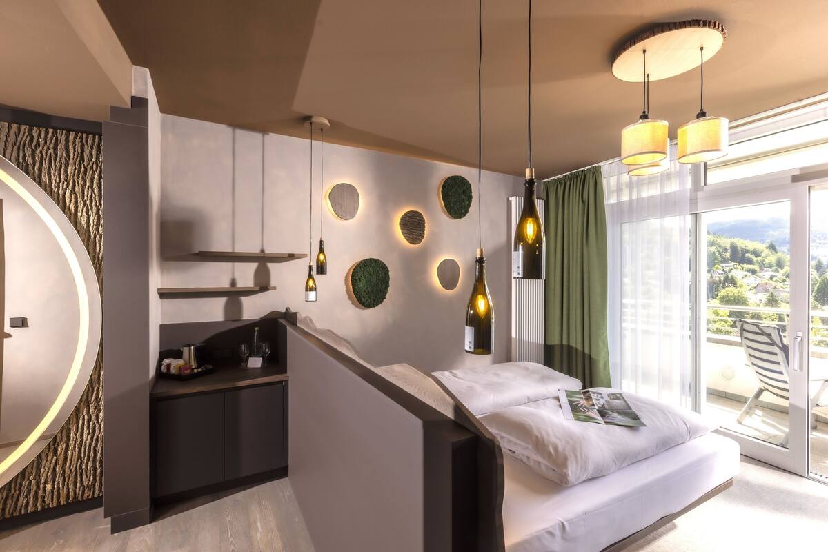 A modern bedroom with a bed, a built-in desk, and a large window with a view.