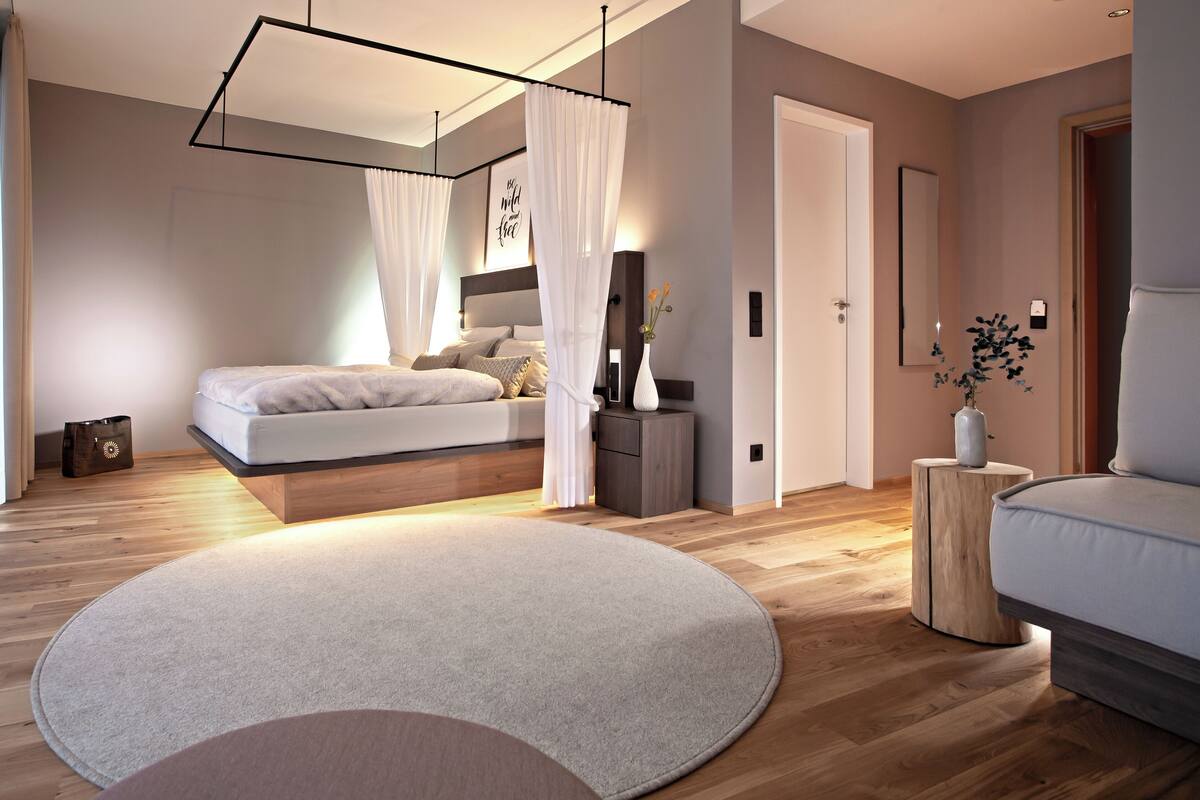 A modern bedroom with a bed, bedside table, and a round rug.
