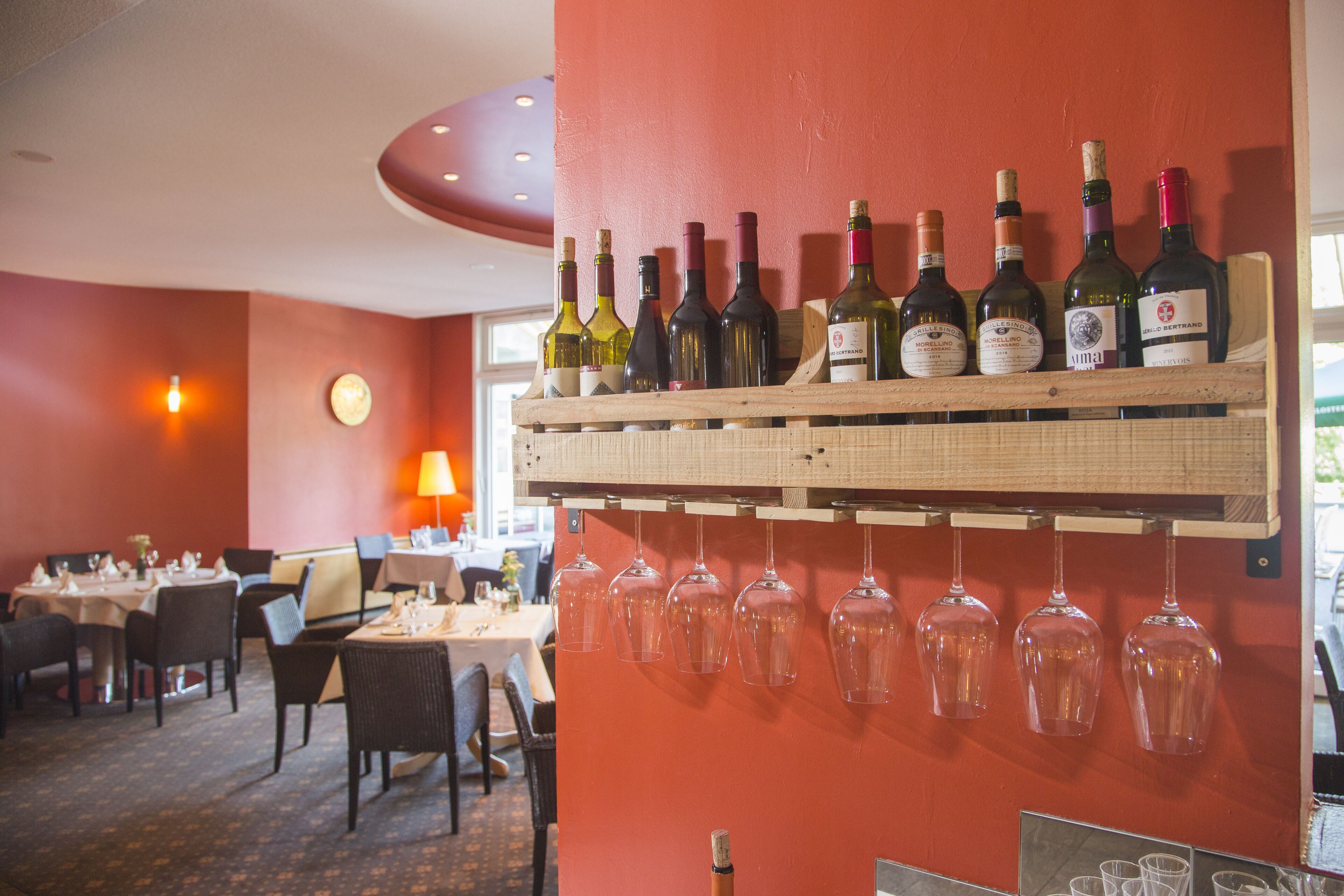 A restaurant interior with a wine rack holding several bottles and glasses.
