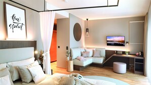 Un dormitorio moderno con cama, sofá, televisión y una obra de arte en la pared.