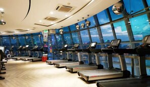 A gym with multiple treadmills aligned against a wall with large windows. - Oriental Riverside Bund View Hotel  (Shanghai)
