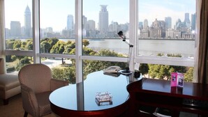 A room with a desk, chair, and large windows offering a city view. - Oriental Riverside Hotel Shanghai (Shanghai)