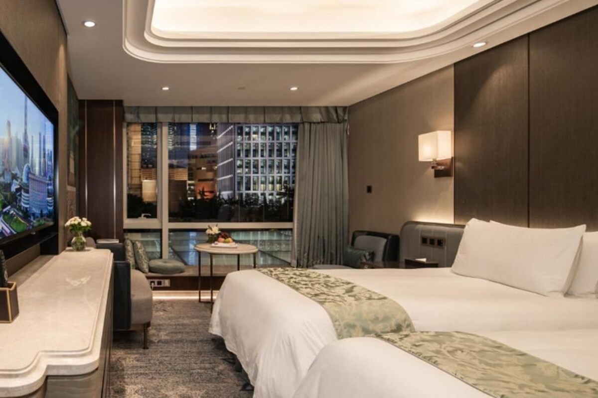 Una camera d'albergo con un letto grande, una scrivania, una sedia, un tavolino e una televisione.