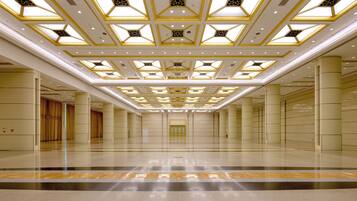 A spacious hotel lobby with a high ceiling featuring geometric patterns and recessed lighting.