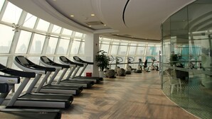 A gym with treadmills aligned along the walls, large windows, and a modern interior design.