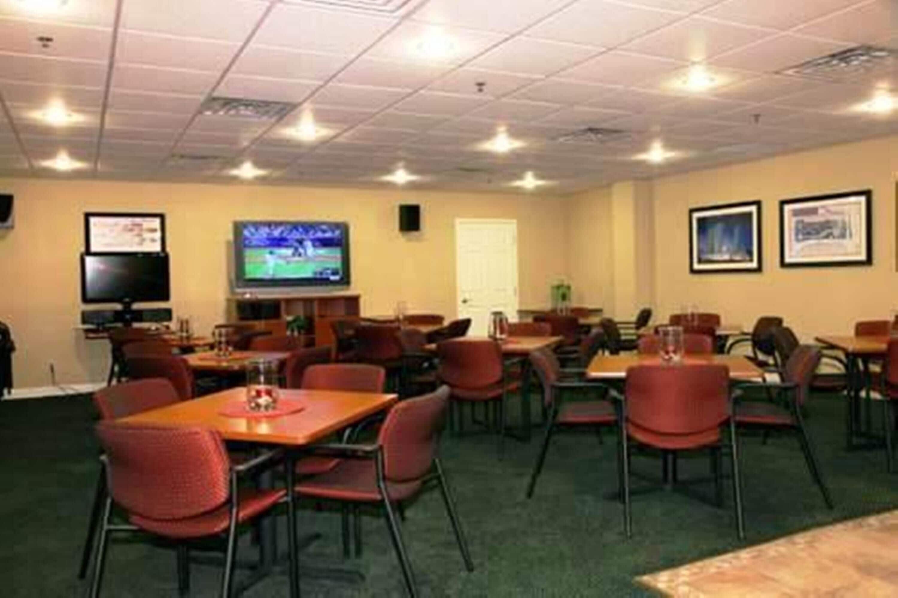 A conference room with tables and chairs, a television, and framed pictures on the walls.