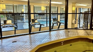 Un área de piscina con suelo de baldosas, un jacuzzi y equipo de ejercicio.