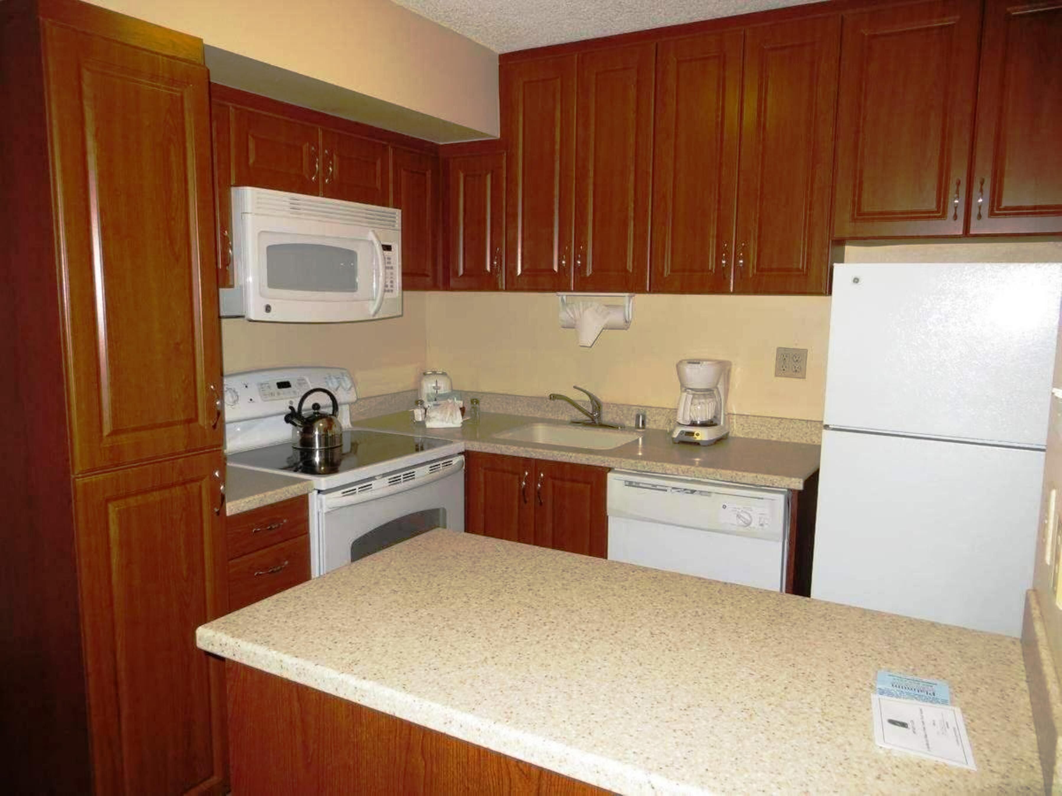A kitchen with wooden cabinets, a microwave, a stove, a dishwasher, and a refrigerator.