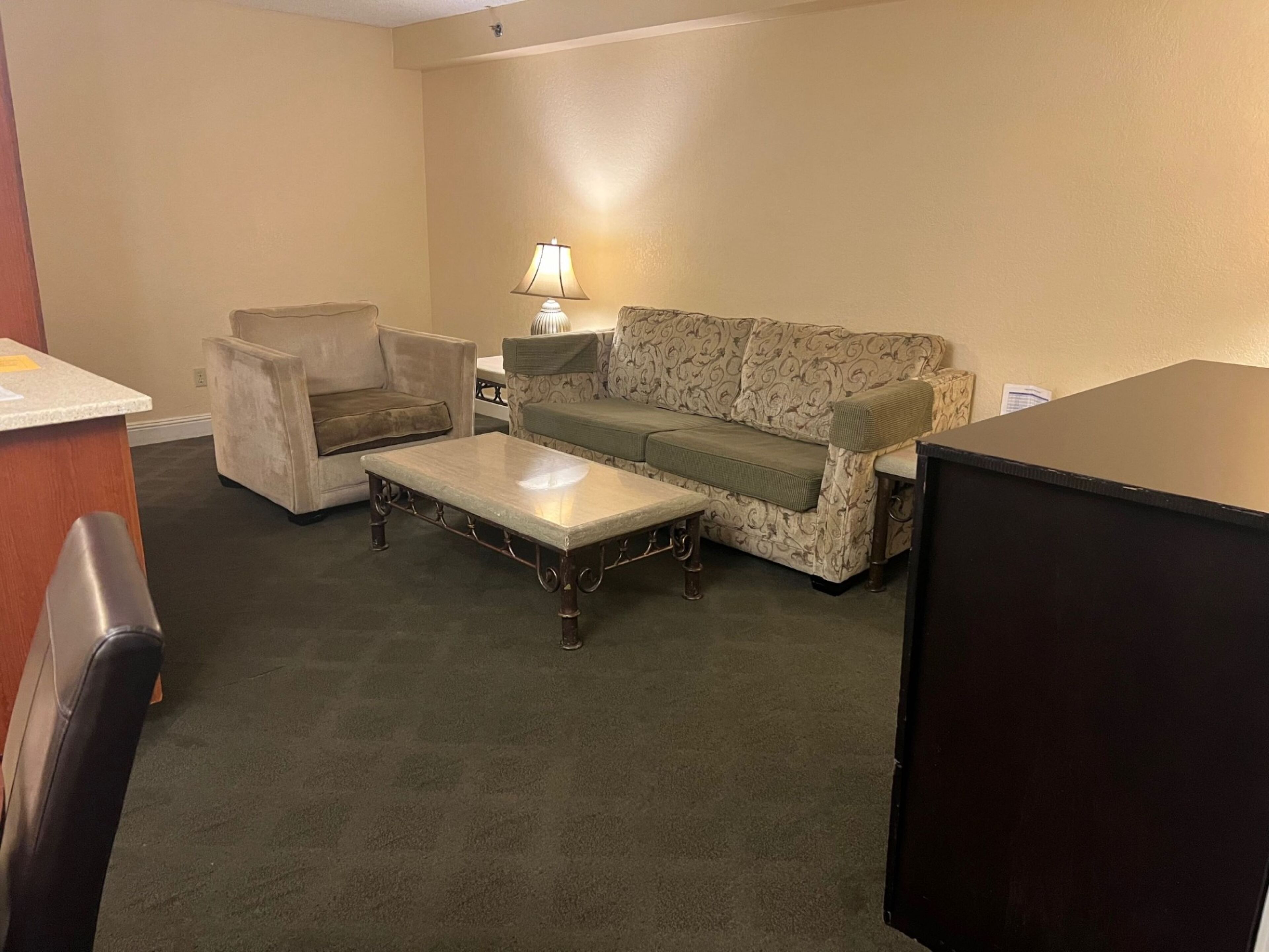 Una sala de estar con sofá, sillón, mesa de centro, lámpara y televisor.