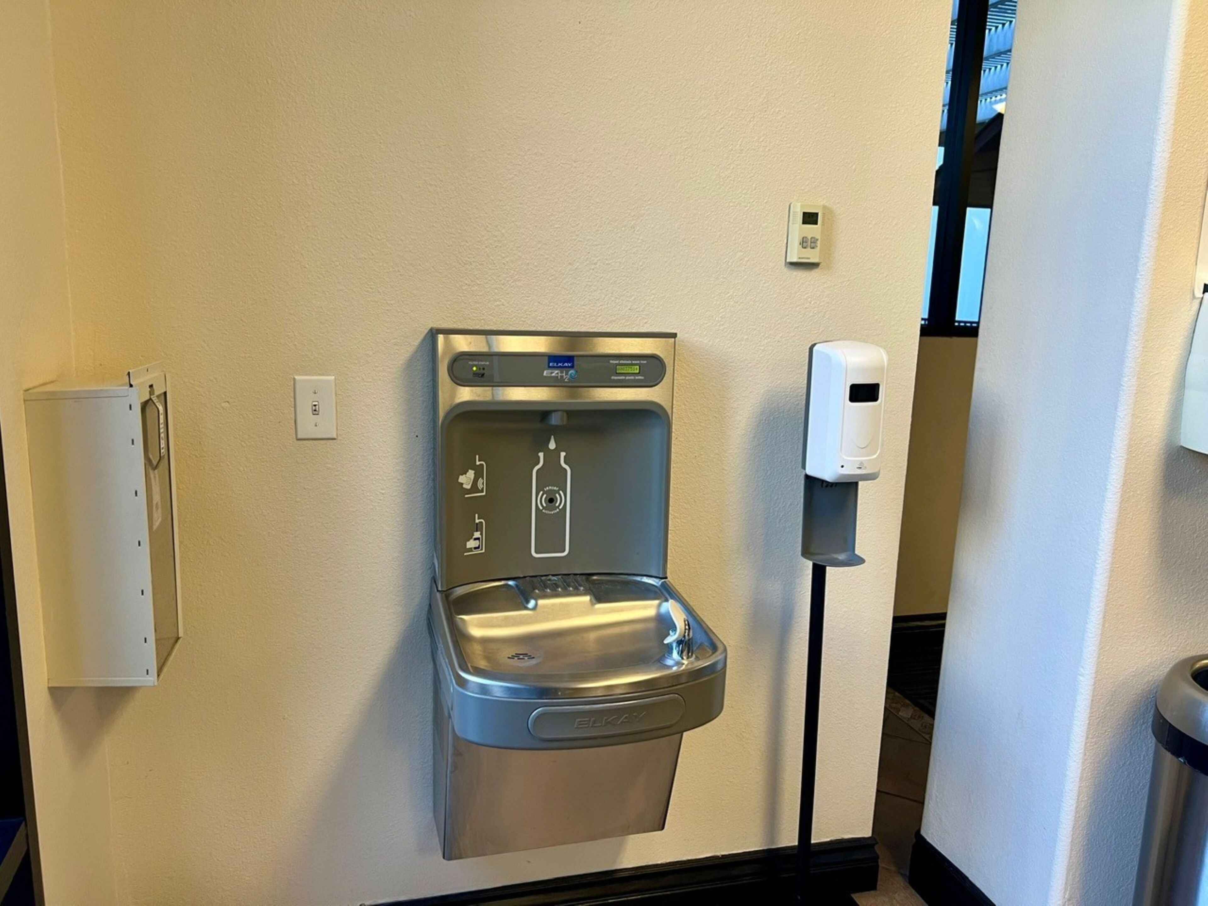 A wall-mounted water dispenser with a soap dispenser beside it.