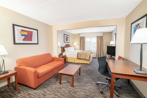 A hotel room with a sofa, a bed, a desk, and a TV.