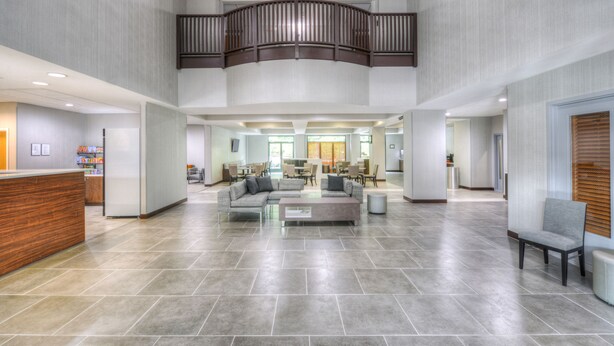 A spacious lobby with a reception desk, seating area, and a staircase leading to an upper level. - Wingate by Wyndham Charlotte Airport I-85/I-485 (Charlotte)