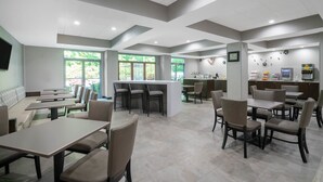 A spacious restaurant with high ceilings, multiple seating areas, and large windows allowing natural light. - Wingate by Wyndham Charlotte Airport I-85/I-485 (Charlotte)