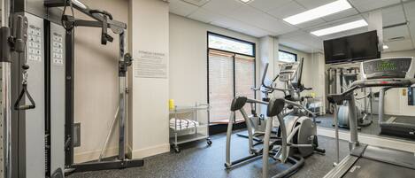 A fitness center with cardio machines, weight machines, and a treadmill.