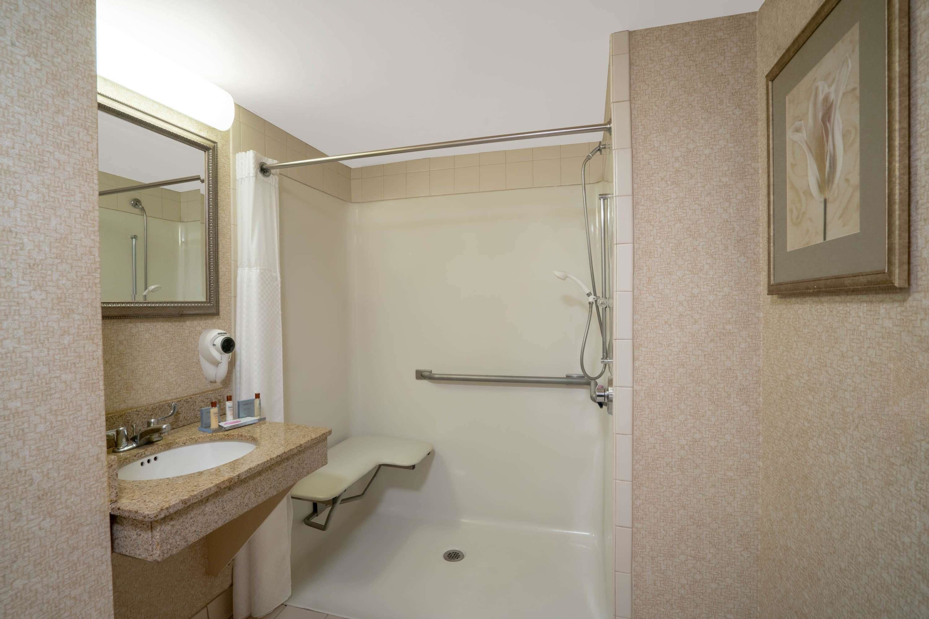 Un baño con lavabo, espejo y ducha.